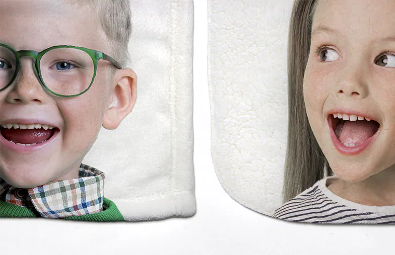 Couverture polaire personnalisée : visages d’enfants souriants imprimés sur un tissu blanc doux.