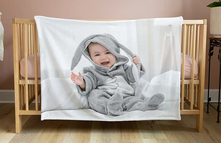 Doudou personnalisé : bébé souriant, vêtu d'un adorable costume de lapin gris, imprimé sur une douce couverture.